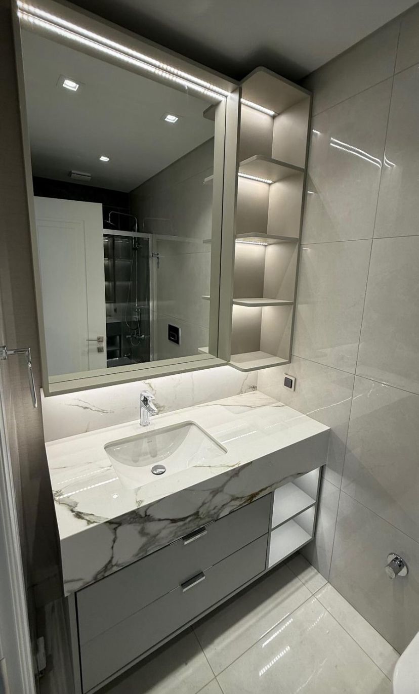 Çağdaş oturma odasında temiz çizgili, mat siyah kulplu sıcak ahşap TV sehpası